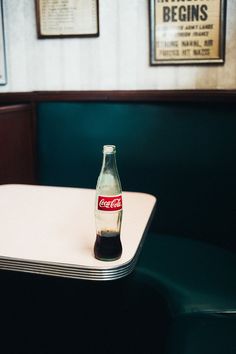 a coca - cola bottle sitting on top of a white table in a diner booth