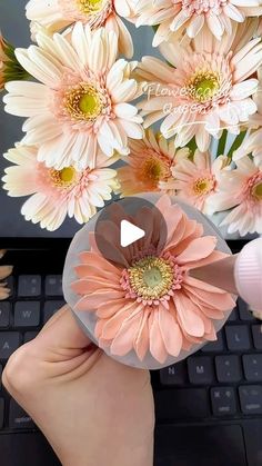 a person is typing on a laptop with flowers in front of them and the keyboard