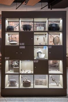 a display case with many different types of kitchen items in glass cases on the wall