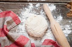 a piece of bread sitting on top of a wooden table next to a rolling pin