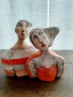 two ceramic figurines sitting on top of a wooden table