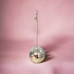 a disco ball on a pink background with a silver stick sticking out of the top