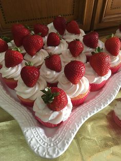 strawberry cupcakes with white frosting and strawberries arranged on a heart shaped platter