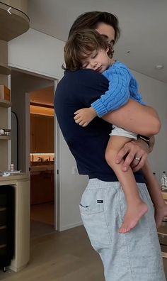 a man holding a child in his arms while standing next to a kitchen counter top