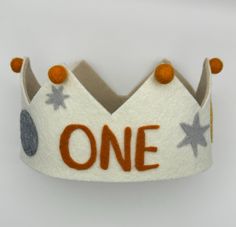 a felt crown with the word one written in orange and grey on it's side