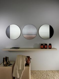 three circular mirrors mounted on the wall above a bench