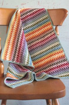 a crocheted blanket sitting on top of a wooden chair