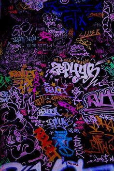 the wall is covered with many different colored graffiti