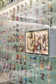 there are many small figurines on display in the glass case behind the television