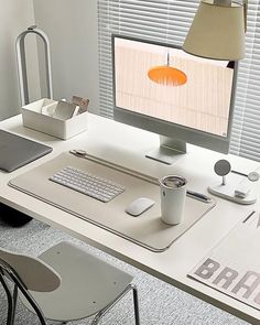 a white desk with a computer, keyboard and mouse on it in front of a window