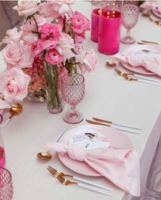 the table is set with pink flowers and gold place settings for an elegant dinner party