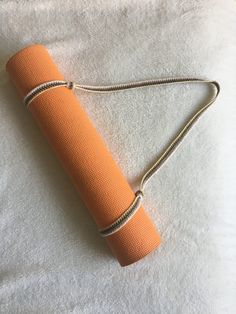 an orange yoga mat laying on top of a white towel with a gold chain around it