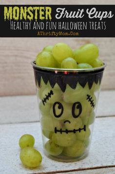 a glass filled with green grapes sitting on top of a counter next to a bunch of grapes