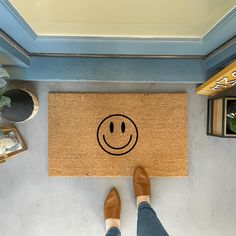 a person standing in front of a door mat with a smiley face drawn on it