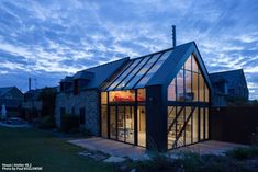 a house that is sitting in the grass with windows on it's roof and glass walls