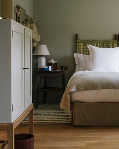 a bed sitting in a bedroom next to a wooden dresser and lamp on top of a hard wood floor