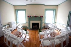 an empty room with white chairs and a fireplace