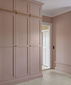 an empty room with pink painted walls and wooden flooring is pictured in this image