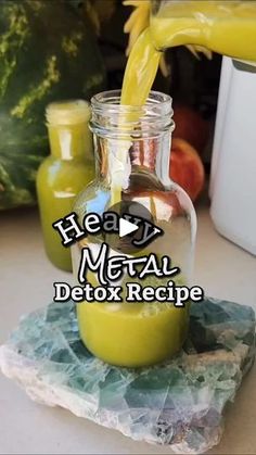 a glass jar filled with green liquid sitting on top of a counter next to fruit