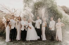 a group of people standing next to each other in front of a water sprinkle