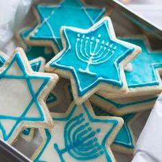 cookies decorated with blue and white icing are in a box on a tablecloth