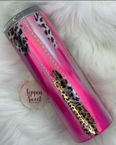 a pink and black leopard print tumbler cup on white fur with the lid open