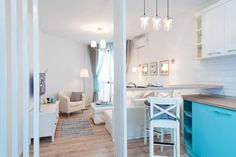 an open kitchen and living room area with white walls, wood flooring and blue cabinets