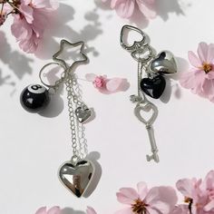 two key chains with charms attached to them next to pink flowers on a white surface