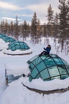 a man sitting on top of a glass dome in the middle of snow covered ground