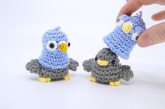 two small crocheted birds are being held by a hand