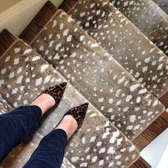 a woman's feet are standing on the carpeted stairs