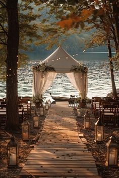 an outdoor wedding setup with lanterns and flowers on the aisle, along with candles lit up