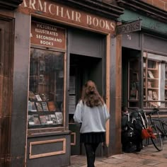 a woman walking down the sidewalk in front of a book store