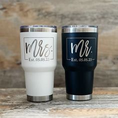 two personalized tumblers sitting next to each other on a wooden table with wood planks