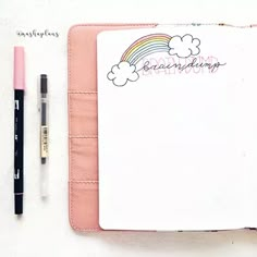 an open notebook with a rainbow and clouds on it