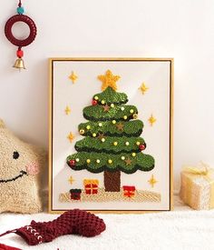 a small christmas tree in a frame next to a knitted teddy bear and other items