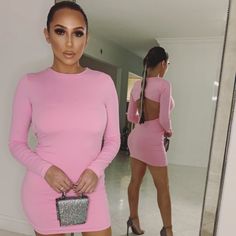 a woman in a pink dress looking at herself in the mirror with her hand on her hip