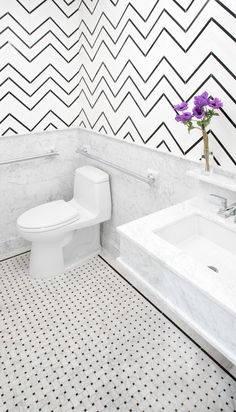 a white toilet sitting in a bathroom next to a sink and a bathtub with a vase on top of it