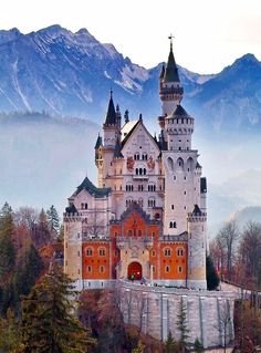 an image of a castle in the middle of the woods with mountains in the background