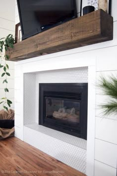 a fireplace with a flat screen tv mounted above it and a potted plant on the mantel