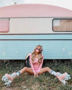 a woman sitting on the ground in front of an old trailer with her legs crossed