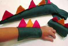 a child's hand is holding onto an arm made out of fabric with red, orange and green spikes on it