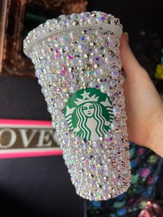 a hand holding a starbucks cup filled with lots of sparkles on it's side