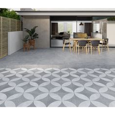 an outdoor living area with concrete flooring and large circular tile design on the ground