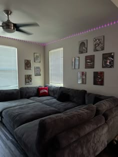 a living room with couches and pictures on the wall above them, along with a ceiling fan