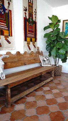 a wooden bench sitting on top of a tiled floor next to a potted plant