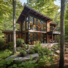 a house in the woods surrounded by trees and plants with lots of windows on it