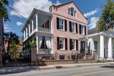 a pink two story house with white trim and balconies