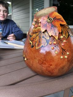 a vase sitting on top of a wooden table next to a person holding a cup