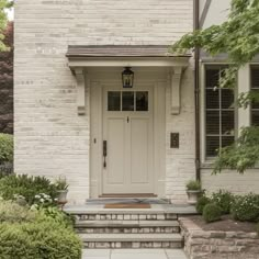 a white brick house with steps leading up to the front door and entryway area